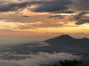 Cerro VerdeHotel Finca Campo Bello的日落时分的云中山景