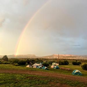 哈奇The Riverside Ranch Motel and RV Park Southern Utah的彩虹在田野上帐篷上