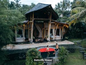 SelatCamaya Bali - Magical Bamboo Houses的两个人站在房子前面