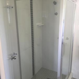WarrenMacquarie Valley Motor Inn的浴室内带玻璃门的白色淋浴