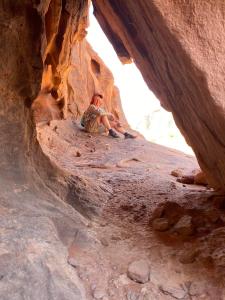 Disah5-hour jeep tour of Wadi Rum highlights的坐在洞穴里的岩石上的人