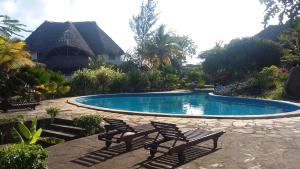 马林迪Villa Fortuna Malindi的房屋前带两把椅子的游泳池
