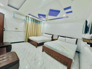 伊斯兰堡Royal Grand Guest House and Residence Islamabad的一间酒店客房,设有两张床和电视