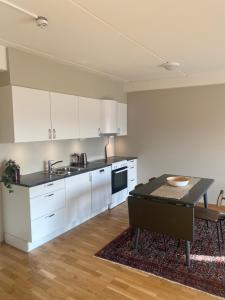 巴杜弗斯Modern apartment in Bardufoss Center - two bedrooms, garage, terrace的厨房配有白色橱柜和桌子