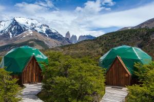 百内三塔巴塔哥尼亚生态露营酒店的两座带绿伞的木制小屋