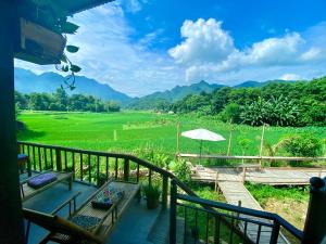 枚州县Meadow Mai Chau Homestay的阳台配有桌子,享有田野美景