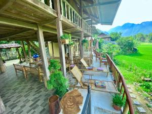 枚州县Meadow Mai Chau Homestay的一个带长椅和桌子的房屋的门廊