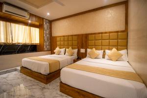 孟买HOTEL BKC PRIME - NEAR US CONSULATE的两张位于酒店客房的床,配有两张sidx sidx单人床