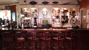 特拉利肯内斯库拉恩酒店的酒吧设有木制酒吧凳和时钟