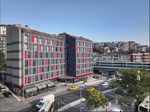 伊斯坦布尔Ramada by Wyndham Istanbul Alibeykoy的城市街道上一座带红色窗户的大型建筑