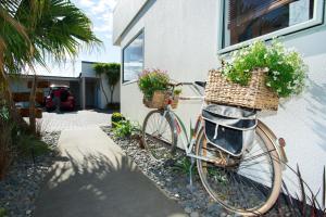 吉斯伯恩Alfresco Motor Lodge的一辆自行车停在房子外面,放着鲜花在篮子里