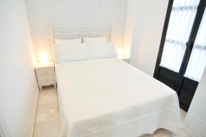 塞维利亚玛卡莲娜公寓的卧室内的白色床、白色床单和枕头