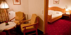 伊姆斯特Appartement & Aparthotel Stern的酒店客房配有一张床、两把椅子和一张桌子