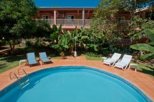 伊瓜苏港波萨达索根特酒店的一个带椅子的游泳池和一个背景房子