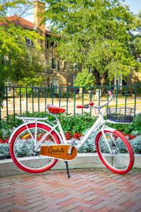 麦迪逊麦迪逊毕业生酒店的一辆红色和白色的自行车停在砖砌的人行道上
