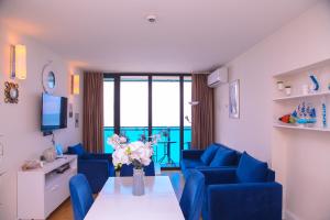 巴统Elegance Sea View Aparthotel In Orbi City Batumi的客厅配有蓝色的沙发和带鲜花的桌子