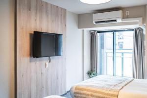 大阪Apartment Hotel 11 Namba Minami III的一间卧室配有一张床,墙上配有电视