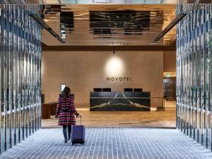 墨尔本Novotel Melbourne Airport的带着行李在机场走的女人