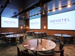 墨尔本Novotel Melbourne Airport的餐厅设有桌椅和投影屏幕