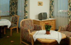 伊姆斯特Appartement & Aparthotel Stern的客厅配有电视、2把椅子和1张桌子