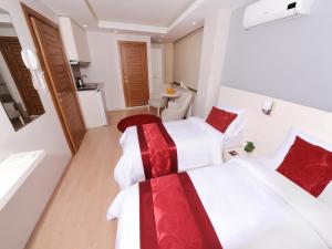 伊斯坦布尔市中心加泽尔公寓式酒店的配有2张位于酒店客房的床,提供白色和红色床单
