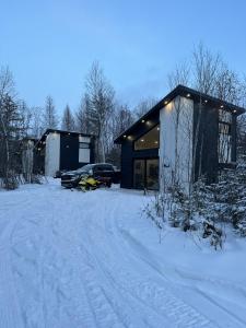 Notre-Dame-des-MontsHebergement du grenier 2 0的雪地中的一座建筑,前面有停车位