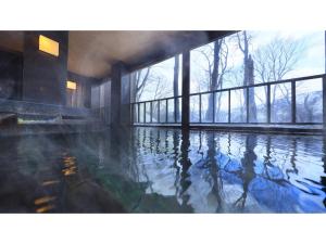 青森Sukayu Onsen Hakkoda Hotel - Vacation STAY 66848v的一座带窗户的建筑里的一个水池