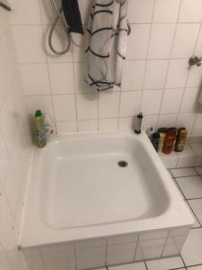 汉诺威Messeapartment Room Agancy Hannover-Garbsen的浴室铺有白色瓷砖,配有白色浴缸。