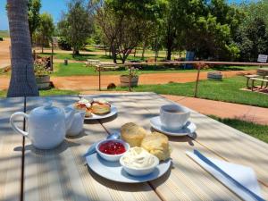 Eighty Mile BeachEighty Mile Beach Caravan Park的餐桌,盘子上放着食物和茶杯