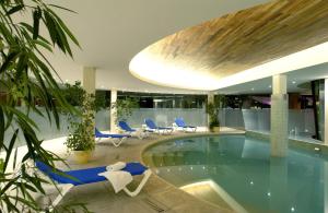 马德普拉塔Hermitage Hotel的一座带蓝色椅子的建筑中的游泳池