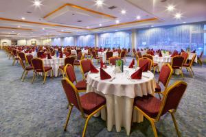 帕莫卡莱帕姆热温泉诊所及Spa酒店的宴会厅配有白色的桌子和带红色餐巾的椅子