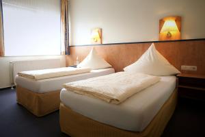 奥伯豪森豪斯友尼恩酒店的两张床位于带两盏挂在墙上的灯的房间