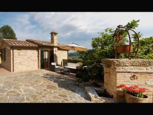 蒙特普齐亚诺La Casina Toscana的石头房子,设有庭院和遮阳伞