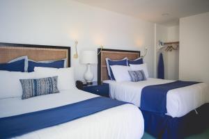 达利城迈洛酒店的一间卧室配有两张带蓝白色枕头的床