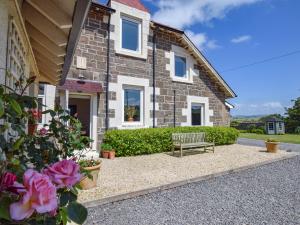 Machrihanish5 bed property in Machrihanish CA291的石头房子前面有长凳