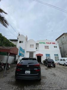 拉合尔Hotel Tulip Inn, Gulberg的停在大楼前停车场的汽车