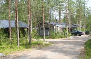 海尔迈Haarusmaa Holiday Apartments Kauhava的树林中的房屋,前面有停车位