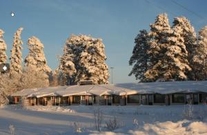 海尔迈哈尔玛嘉实坎洛玛公寓酒店的一座被雪覆盖的建筑,在树前