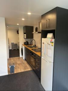 摩斯吉尔Tiny Home in Mosgiel的厨房配有白色冰箱和木制橱柜。