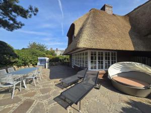 坎彭Ferienhaus Cäcilienhof West的茅草屋顶房屋,配有桌椅