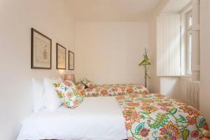 里斯本阿法玛舒适型公寓的一间卧室配有两张带色彩缤纷枕头的床