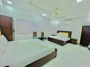 伊斯兰堡Royal Grand Guest House and Residence Islamabad的酒店客房设有两张床和投影屏幕