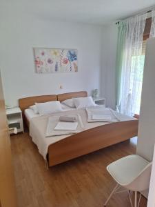 拉布Apartments and rooms with parking space Palit, Rab - 22221的一间卧室配有一张大床和一把椅子