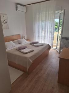 拉布Apartments and rooms with parking space Palit, Rab - 22221的一间卧室设有一张床和一个大窗户