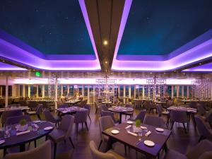 直布罗陀直布罗陀萨博恩酒店的餐厅配有桌椅和紫色照明