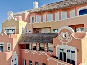 坎昆Casa Tortugas Boutique Hotel, An Authentic Hidden Gem in Cancun的粉红色的建筑,茅草屋顶