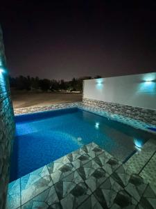 Al RahbaLuxury Farmhouse Near Yas Island With Swimming Pool, BBQ Area & Majlis的夜间在房子里的一个游泳池