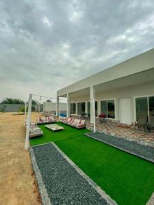 Al RahbaLuxury Farmhouse Near Yas Island With Swimming Pool, BBQ Area & Majlis的前面有绿色草坪的房子