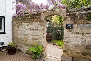 沃里克Daisy Cottage的石墙中的拱门,花紫色