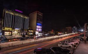 苏莱曼尼亚Mihrako Hotel & Spa的繁忙的城市街道,晚上停有车辆